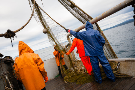 Fishermen in protective suits on deck Fishing vessel. Morning time.の写真素材
