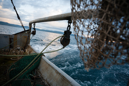 Fishing nets are on the deck of a small fishing vessel. Evening time.の写真素材