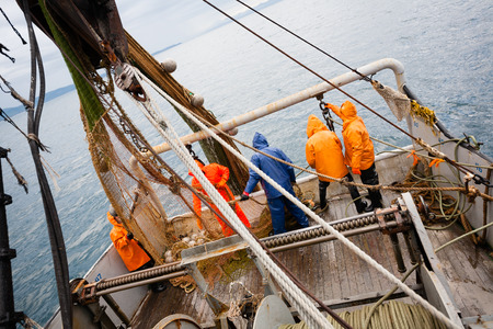 Fishermen in protective suits on deck Fishing vessel. Morning time.の写真素材