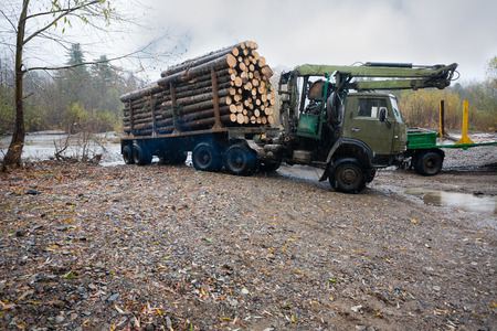 Heavy truck for transportation of logs standing on the bank of the river. Autumn rain. Russian Far East.の写真素材