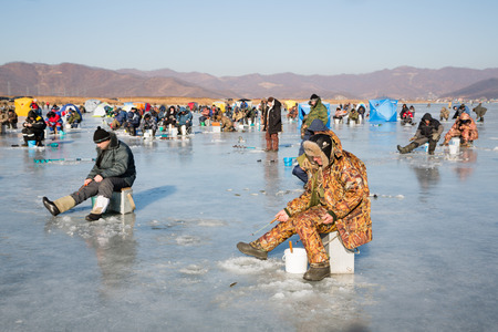 NAKHODKA, RUSSIA - DECEMBER 19, 2015: In winter, people catch fish from under the ice in the river Partizanskay. Fishing smelt and saffron cod is a popular activity among the local people.のeditorial素材