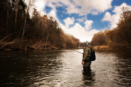 Fisherman catches a trout on the river in autumnの写真素材