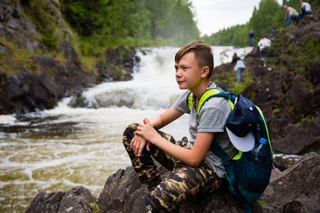 Portrait of a boy standing near a waterfall in the summerの写真素材
