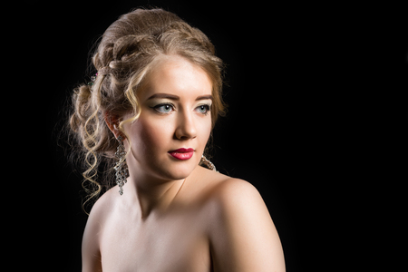 Fashionable make-up for a young girl with a beautiful hairdress on a black backgroundの写真素材