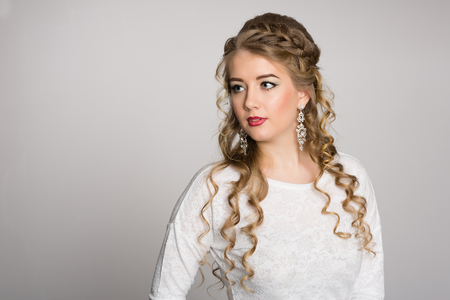 Portrait of a pretty girl with a fashionable hairstyle with curls on a gray backgroundの写真素材