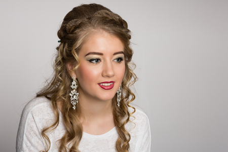 Cheerful pretty girl with a fashionable hairstyle with curls on a gray backgroundの写真素材