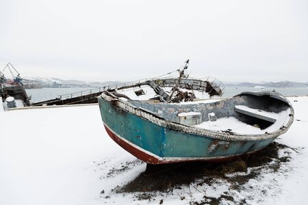 An old broken lifeboat lies on a pier in winter. Environmental pollution.の写真素材