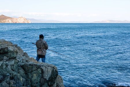 Fisherman catches fish from the rocks on the seaの写真素材