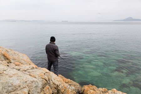 Fisherman on sea fishing on the rocks in the early morning.の写真素材