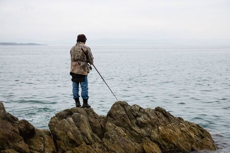 Fisherman catches fish on the rocks in the morning の写真素材