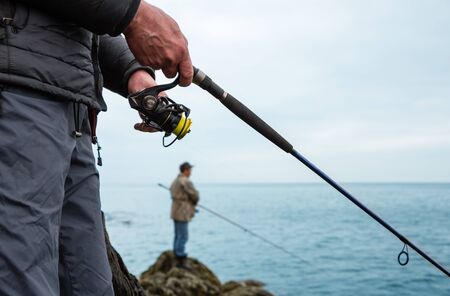 Fishermen catch salmon in the sea from the rocksの写真素材