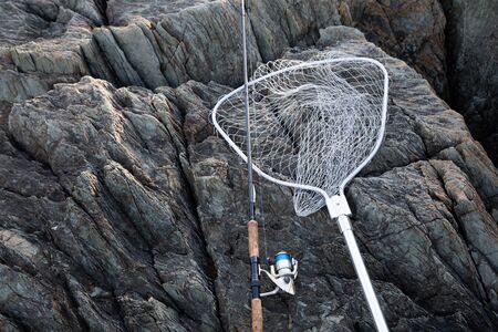 Spinning and landing net on a rocky seashoreの写真素材