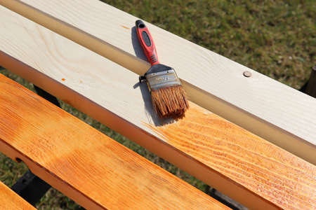 Brush on the beam. Painting a wooden beam with brown varnish.