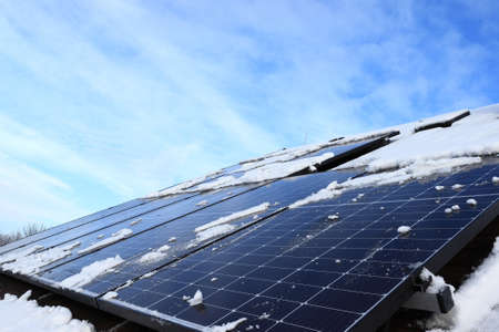 The performance of photovoltaic panels is affected by the weather. Snow limits the production of green energy. Electricity generation on the roof of the house.の写真素材