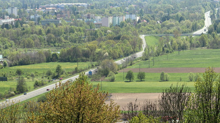 Panoramic view of highway with overpass. Trees and fields in the foreground, city in the background.の写真素材