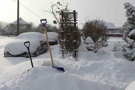 Snow calamity.  Snow calamity, shovels put away in the drift. Snowy country road and parked cars.の写真素材
