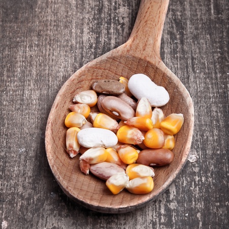wooden spoon with beans and corn on wooden plankの写真素材