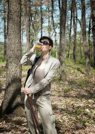 Female tourist drinking juice from bottle at forestの写真素材