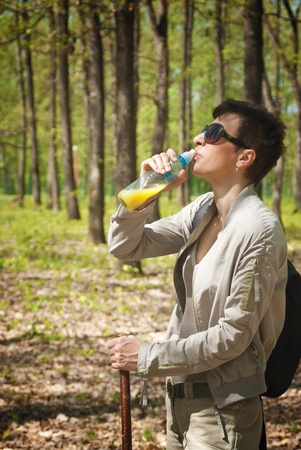 Female tourist drinking juice from bottle at forestの写真素材