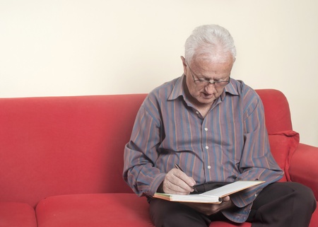 Senior writing in notebook.の写真素材