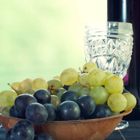 bottle of wine with grape leaves on wooden tableの写真素材