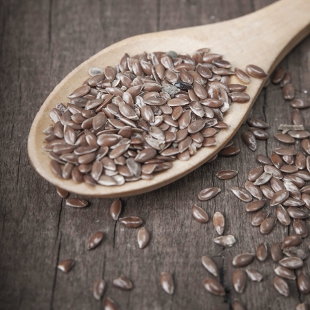 wooden spoon with brown flax seeds on itの写真素材