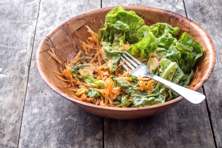Green salad with grated carrots on table,half emptyの写真素材