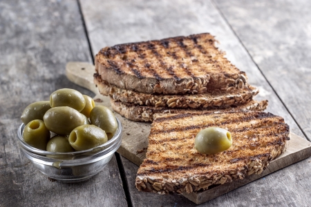 toasted bread and olives on table in close upの写真素材