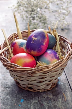 Colored easter eggs in basket on wooden tableの写真素材