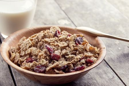 A bowl of cereal with cranberries on the tableの写真素材