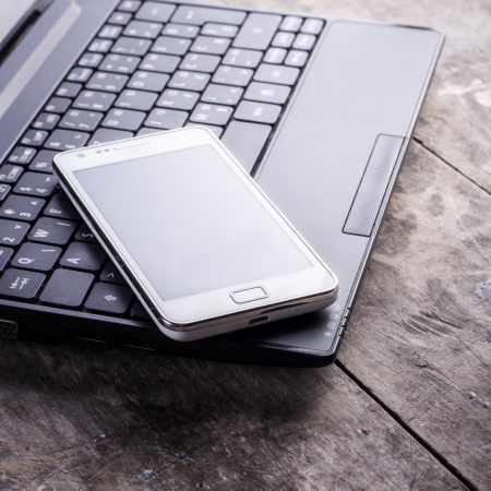 smartphone and laptop on old wooden tableの写真素材