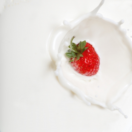  strawberrie falling into milk forming a crown splash.の写真素材