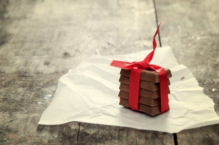 Chocolate pieces in decorative ribbon on wooden tableの写真素材
