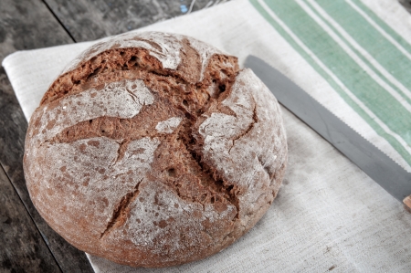 Homemade bread and knife on wooden table