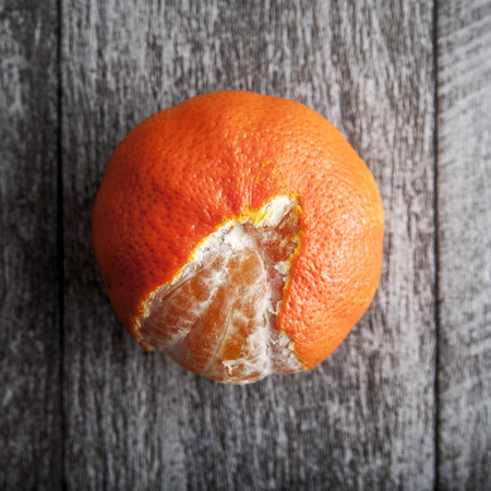 freshly peeled tangerine/orange on a wooden tableの写真素材