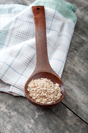 Soy flakes in wooden spoon on old wooden plankの写真素材