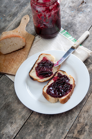 Plum jam with bread on wooden plankの写真素材