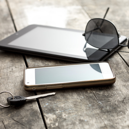 mobile phone, tablet and sunglasses on table, backlitの写真素材