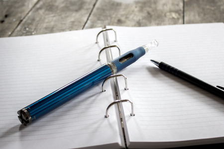 E-cigarette on notepad on wooden tableの写真素材