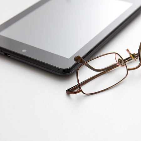 Tablet computer and eyeglasses on desk, close upの写真素材