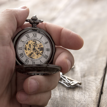 close up of hands with vintage pocket watch over wooden backgroundの写真素材