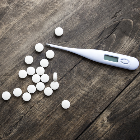Thermometer and  pills  on table. Cold and flu concept