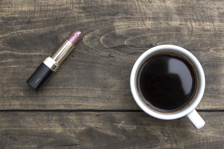 Red Lipstick and cup of coffee on wooden table, from aboveの写真素材