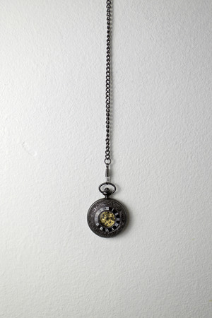 Old pocket watch hanging on the white wall