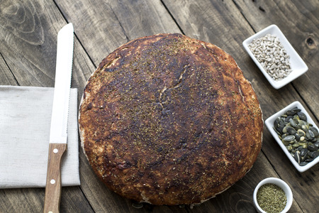 Homemade bread and seeds on wooden table, from above