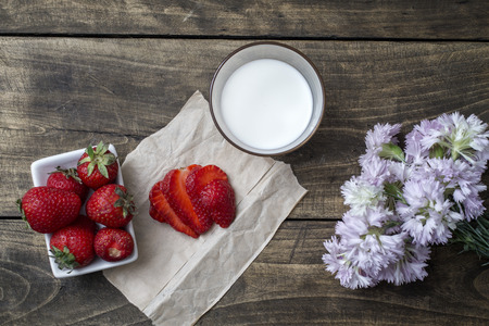 Fresh ripe strawberry in bowl and milk over wooden table background. Top viewの写真素材