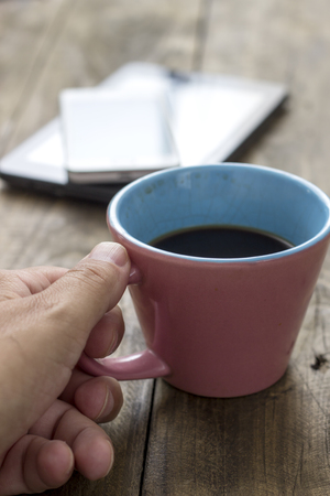 hand  holding cup of coffee on wooden background, close upの写真素材