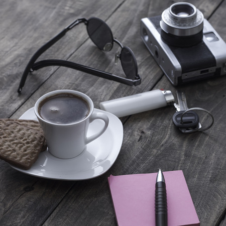 Analogue photo camera on a table with coffee and paper notes