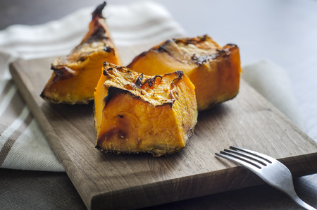 Roasted pumpkin on a wooden  background, close upの写真素材