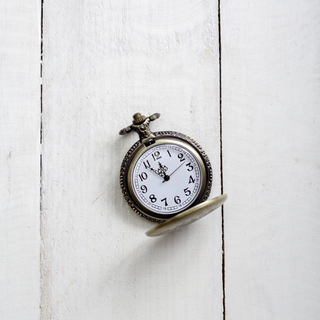 antique  pocket watch with  chain against rustic aged wooden background with hands approaching twelve o'clockの写真素材